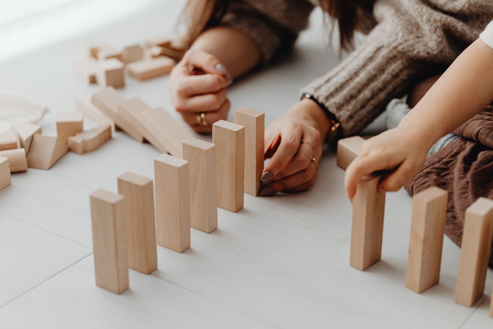 Les mains d'un adulte et d'un enfant assemblent des blocs en bois
